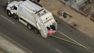 Philadelphia trash truck with police tape blocking off te roadway behind it after a body was found by sanitation workers on July 1, 2021,