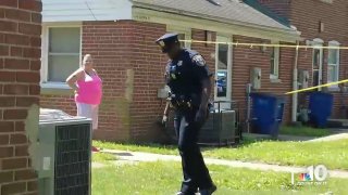 A Wilmington police officer walks across a lawn as a woman watches on during the investigation into the shooting death of TikTok creator Matima Miller, known by his nickname, "Swavy."