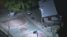 An empty basketball court where a girl was fatally shot is illuminated by floodlights.