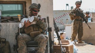 In this image provide by the U.S. Marine Corps, a Marine assigned to the 24th Marine Expeditionary Unit (MEU) calms an infant during an evacuation at Hamid Karzai International Airport, in Kabul, Afghanistan, Friday, Aug. 20, 2021.