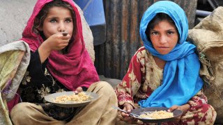 Afghan children, who salvage recyclable items from garbage to make a living, eat a meal of rice in Jalalabad on June 30, 2013.