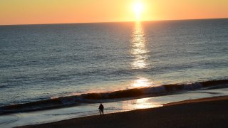 REHOBOTH BEACH, DE – NOVEMBER 29: A photographer arranges a tripod beside the ocean to document the sunrise on November 29, 2020 in Rehoboth Beach, Delaware. Due to the coronavirus (COVID-19) pandemic, face masks are required on the boardwalk and strongly recommended on the beach. (Photo by Mark Makela/Getty Images)