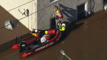 A man climbs out of a window and down a ladder as awaiting rescuers attempt to help him to a nearby boat as floodwaters hit Bridgeport, Pennsylvania, on Thursday, Sept. 2, 2021.