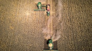 A farmer operates a combine harvester as he unloads wheat into a grain cart during a harvest at a farm near Gunnedah, New South Wales, Australia, on Tuesday, Nov. 10, 2020.