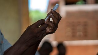 Person holding malaria vaccine shot