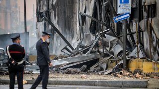 Carabinieri officers stand on the site of a plane crash, in San Donato Milanese suburb of Milan, Italy