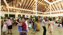 A rendering shows a woman holding a child as they smile. Behind them, children run around and adults dance in an events room.