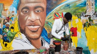 Photos shows local artist Randall Whitfield working a new mural honoring George Floyd in Philadelphia after the first was defaced with symbols of white supremacy.