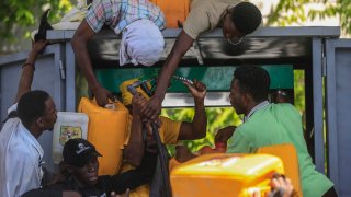People push as they try to get their gallons filled at a gas station in Port-au-Prince, in Port-au-Prince, Haiti,