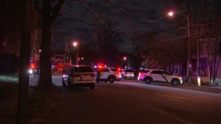 Multiple Philadelphia Police Department SUVs turn on their lights as they park near the intersection where a person was found dead in a burning car.