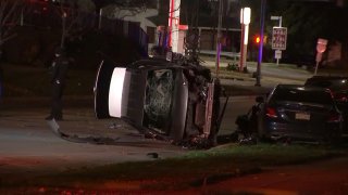 A car rests on its side and has front-end damage and a shatter windshield.