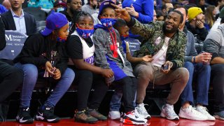 Rapper Meek Mill, right, sits courtside children from families that have been adversely affected by the criminal justice system during the first half of an NBA basketball game the Miami Heat and the Philadelphia 76ers, Wednesday, Dec. 15, 2021, in Philadelphia.