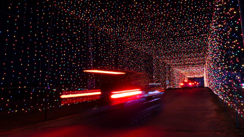 Passenger vehicles move through a tunnel of holiday lights