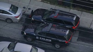 An aerial shot shows two police SUVs parked next to each other on a residential street.