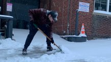 A man crouches down to shovel snow on Levering Street in Philadelphia's Manayunk neighborhood.