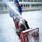A man in a jacket uses a snow blower to clear snow in Newark, Del.