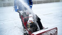 A man in a jacket uses a snow blower to clear snow in Newark, Del.