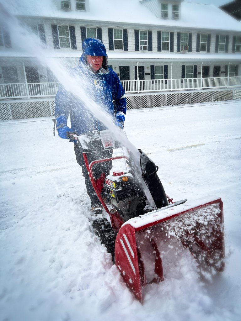 A man in a jacket uses a snow blower to clear snow in Newark, Del. 