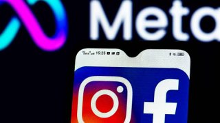 The Facebook and Instagram logos displayed on a smartphone with the Meta Platforms logo pictured in the background.