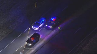 An aerial shot shows two police SUVs with their lights on parked next to another SUV.