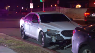 A white sedan is parked next to a sidewalk. It has damage to the front passenger side.