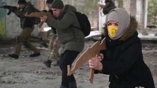 People hold replicas of Kalashnikov rifles as they take part in a military drill of the Ukrainian Territorial Defence Forces, the military reserve of the Ukrainian Armed Forces, outside Kyiv on February 19, 2022.
