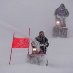Course workers blow snow from the men's giant slalom course as the snow comes down at the alpine ski venue at the 2022 Winter Olympics, Sunday, Feb. 13, 2022, in the Yanqing district of Beijing.