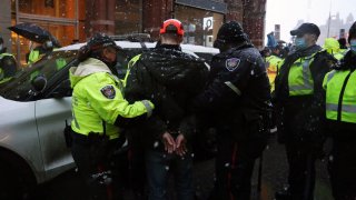 Police officers escort an arrested protester