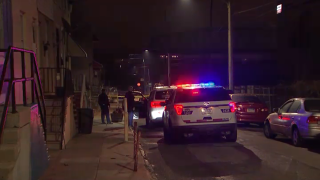 Police officers stand on a sidewalk and next to their parked SUVs.