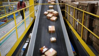 A worker passes a conveyor of fast moving packages on their way to delivery trucks during operations on Cyber Monday at Amazon’s fulfillment center in Robbinsville, New Jersey, November 29, 2021.