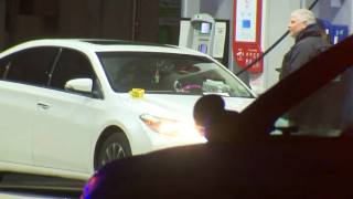 A white sedan next to a gas pump has an evidence marker on it.