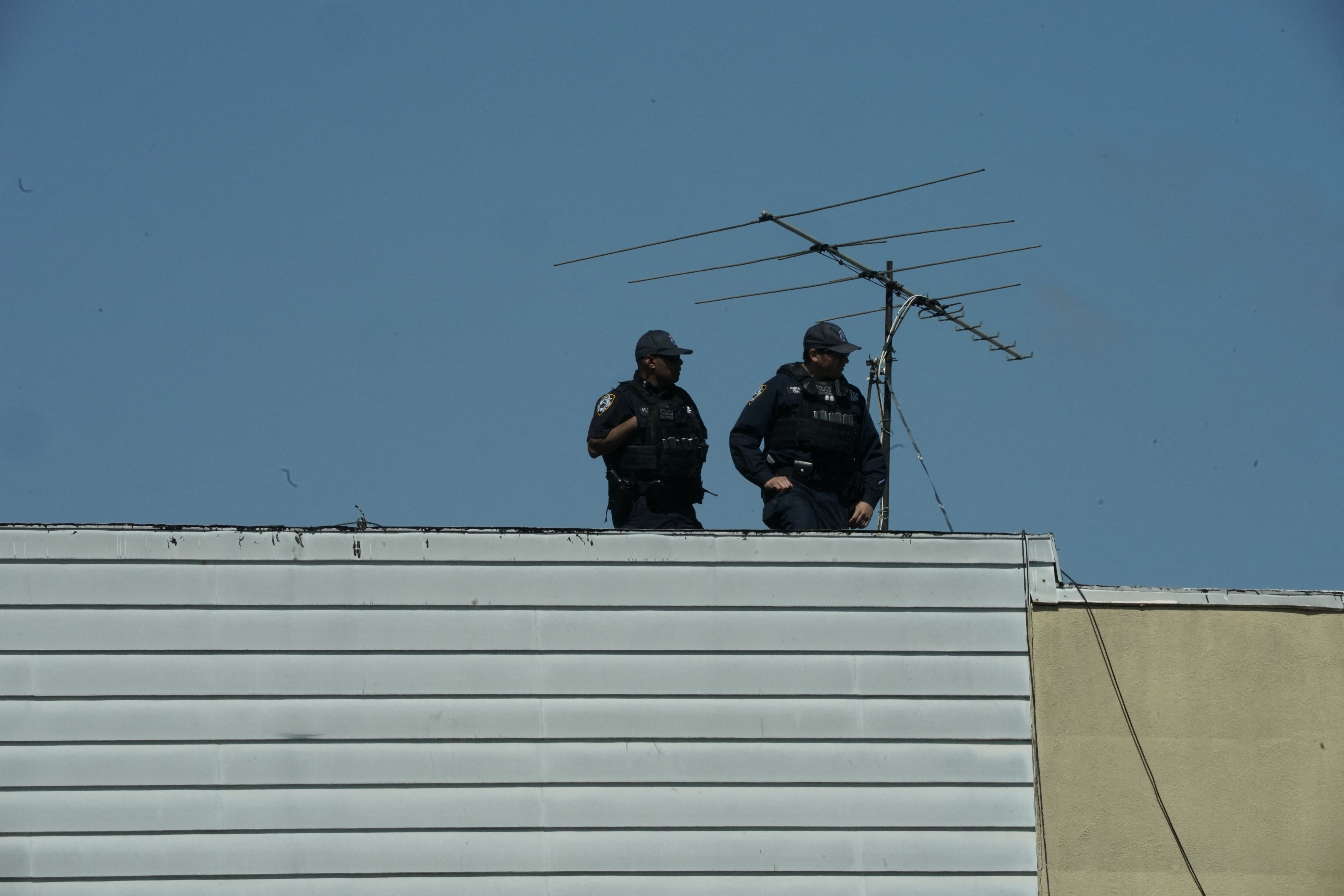 Members of the New York Police Department look on from a rooftop after at least 16 people were injured during a rush-hour shooting at a subway station Brooklyn, New York, on April 12, 2022.