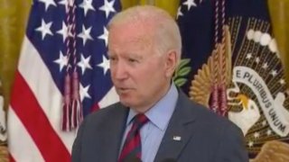 President Joe Biden standing in front of flags.