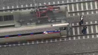 A SEPTA regional rail train on tracks with police officers standing behind.