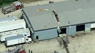 An aerial view shows the roof of a repair shop partially sheared off.