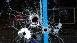 Bullet holes from a prior shooting are still present in a storefront window