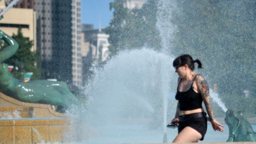 Woman walks through water as people come to the fountain of Logan Square to beat the heat of a nice summer day, in Philadelphia.