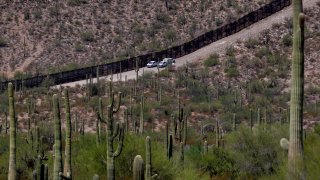 FILE – U.S. Customs and Patrol Patrol agents sit along a section of the international border wall that runs through Organ Pipe Cactus National Monument, Thursday, Aug. 22, 2019 in Lukeville, Ariz.