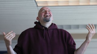 John Fetterman with his arms out at his sides appears to laugh