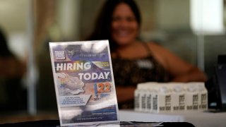 FILE - A hiring sign is placed at a booth for prospective employers during a job fair, Sept. 22, 2021, in the West Hollywood section of Los Angeles.
