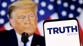 The Truth social network logo is seen on a smartphone in front of a display of former U.S. President Donald Trump in this picture illustration taken February 21, 2022.