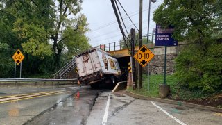 A truck wedged under a rail bridge by a SEPTA station