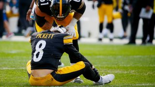 Kenny Pickett #8 of the Pittsburgh Steelers is checked on by Mason Cole #61 after being injured against the Tampa Bay Buccaneers during the third quarter at Acrisure Stadium on October 16, 2022 in Pittsburgh, Pennsylvania.