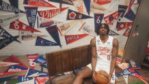 Tyrese Maxey hold basketball in uniform in front of Sixers pennants