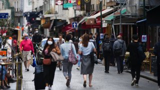 Pedestrians wear protective face masks while passing stores and cafes on Rue Montorgueil in Paris, France, on Wednesday, Aug. 26, 2020.