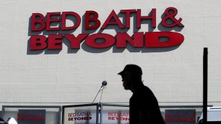 a man walks by a Bed, Bath and Beyond storefront.