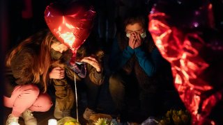 Women pause at a memorial at a vigil honoring the victims of a shooting at the Star Ballroom Dance Studio on Monday, Jan. 23, 2023, in Monterey Park, Calif.