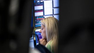 A stock trader at the Frankfurt stock exchange watches the price development on her monitor.