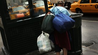 A woman looks through a garbage can in Manhattan in New York City.