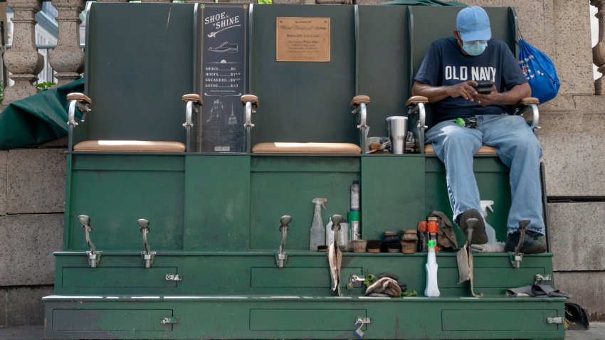NEW YORK, NEW YORK – AUGUST 28: A shoe shine employee wearing a mask waits for customers near Grand Central Station as the city continues Phase 4 of re-opening following restrictions imposed to slow the spread of coronavirus on August 28, 2020 in New York City. The fourth phase allows outdoor arts and entertainment, sporting events without fans and media production.